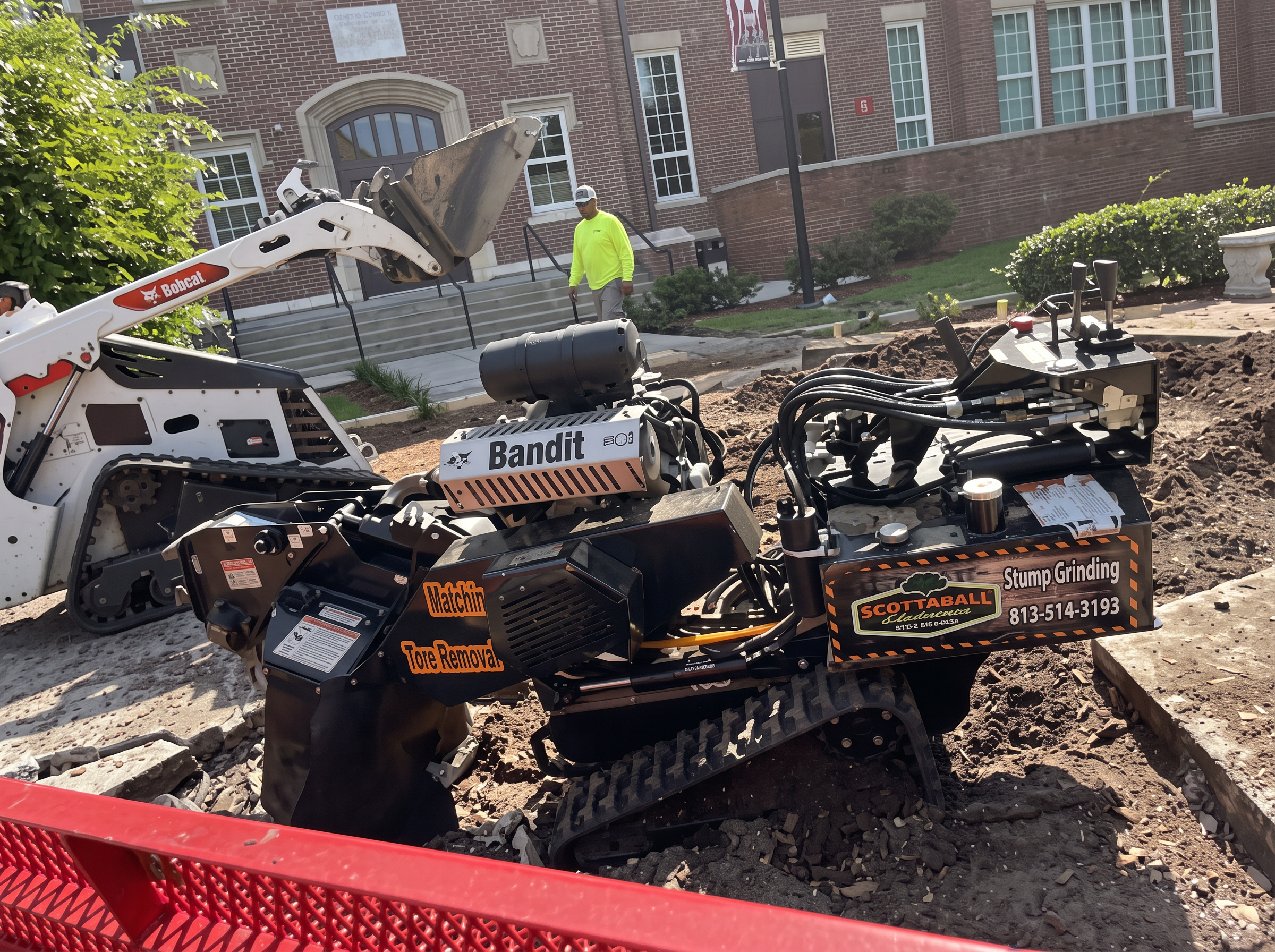 Crew with a Bobcat and grinder on a commercial job site